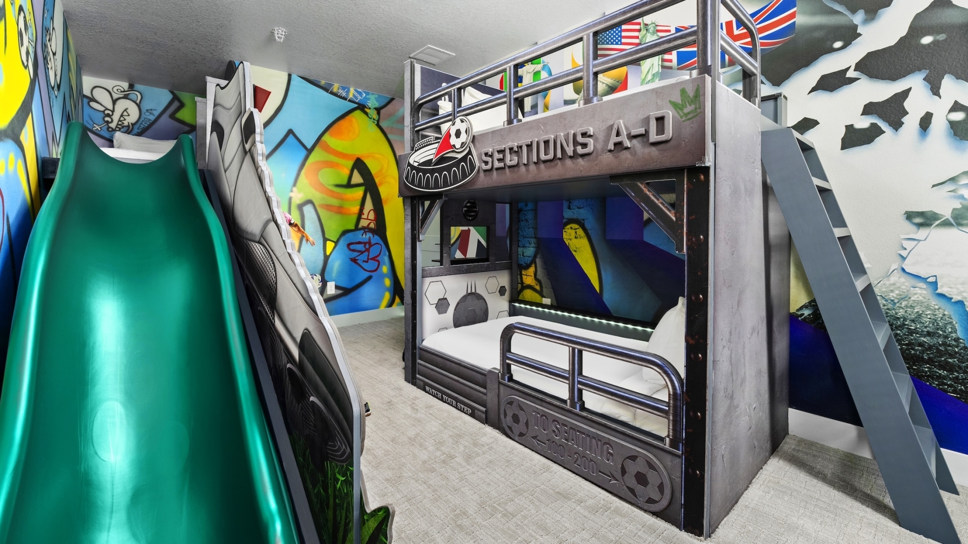 A soccer-themed children's bedroom featuring a stadium-style bunk bed with industrial railings, a green slide, and vibrant graffiti-style wall murals.