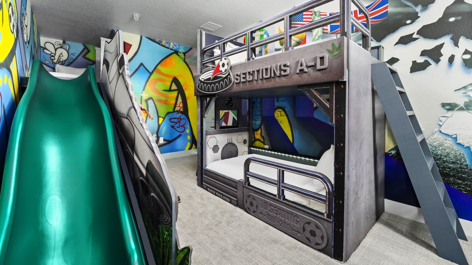 A soccer-themed children's bedroom featuring a stadium-style bunk bed with industrial railings, a green slide, and vibrant graffiti-style wall murals.