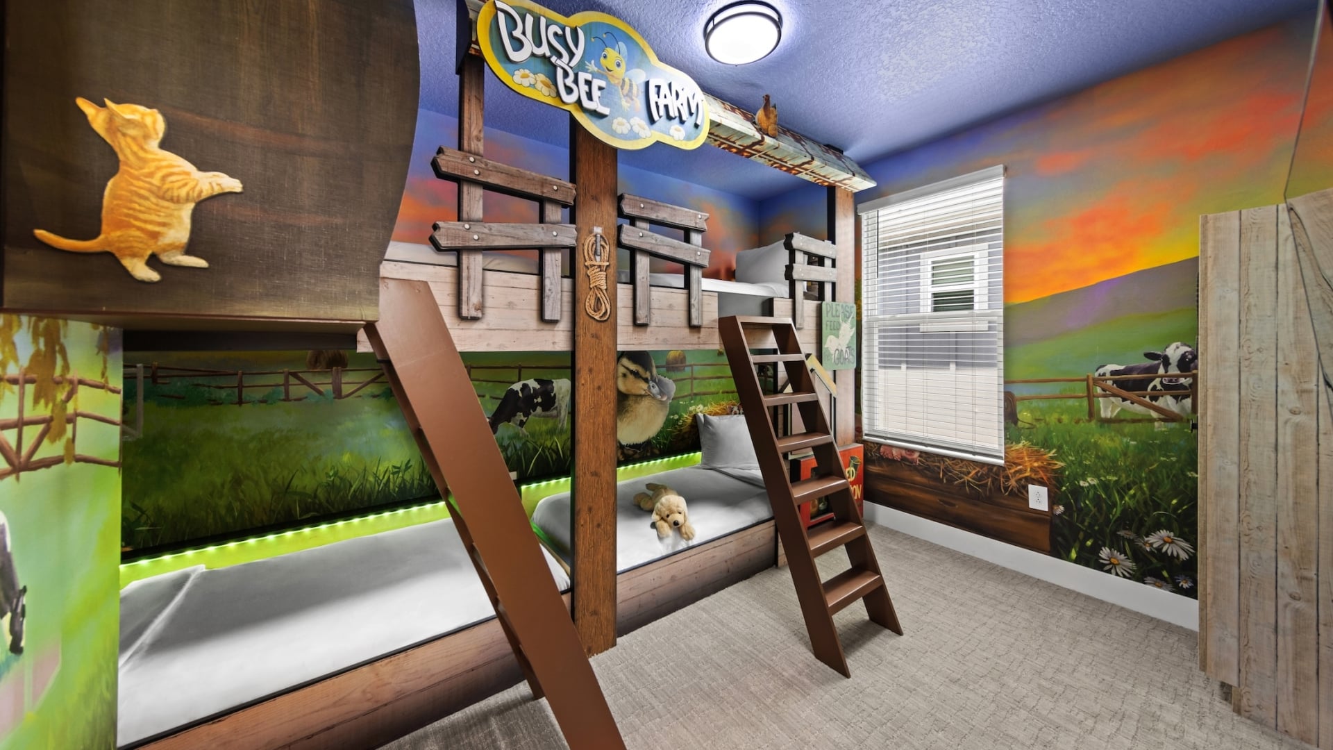 A farm-themed children's bedroom featuring a wooden fence-style bunk bed with a "Busy Bee Farm" sign and wall murals of cows and fields at sunset.