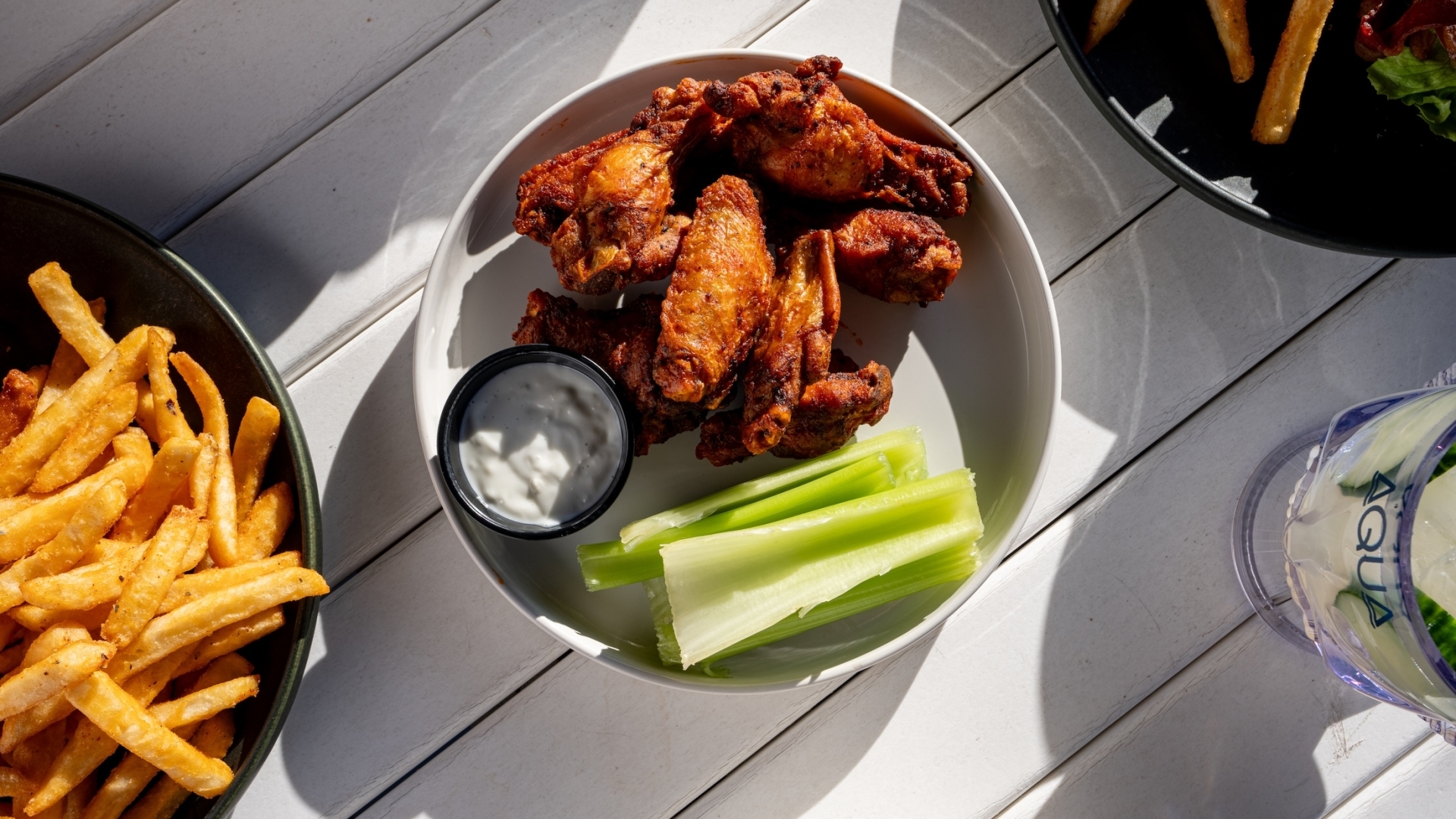A plate of crispy seasoned chicken wings served with fresh celery sticks and a side of blue cheese dressing.