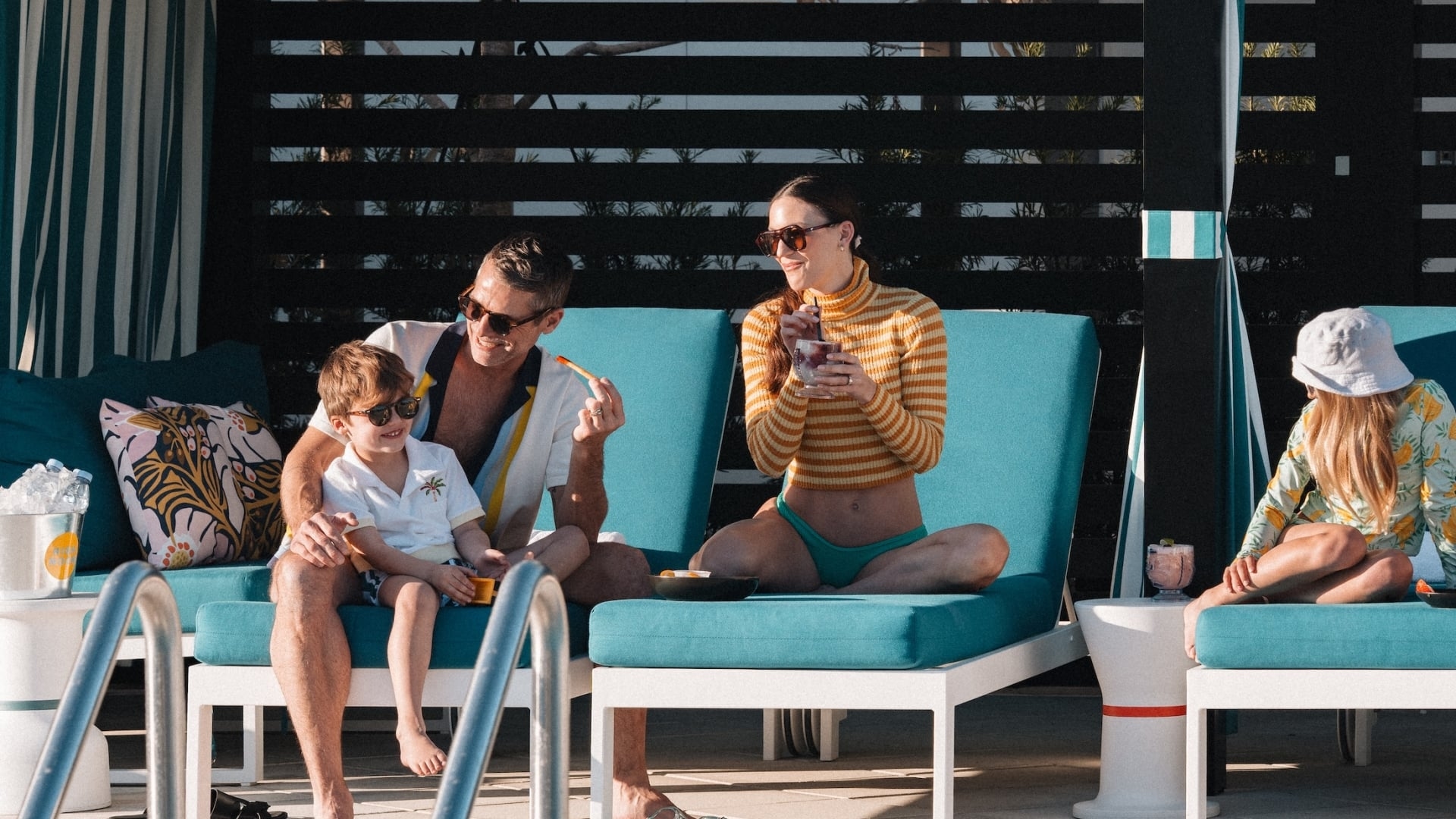 A family relaxes on teal lounge chairs inside a private poolside cabana at the resort.