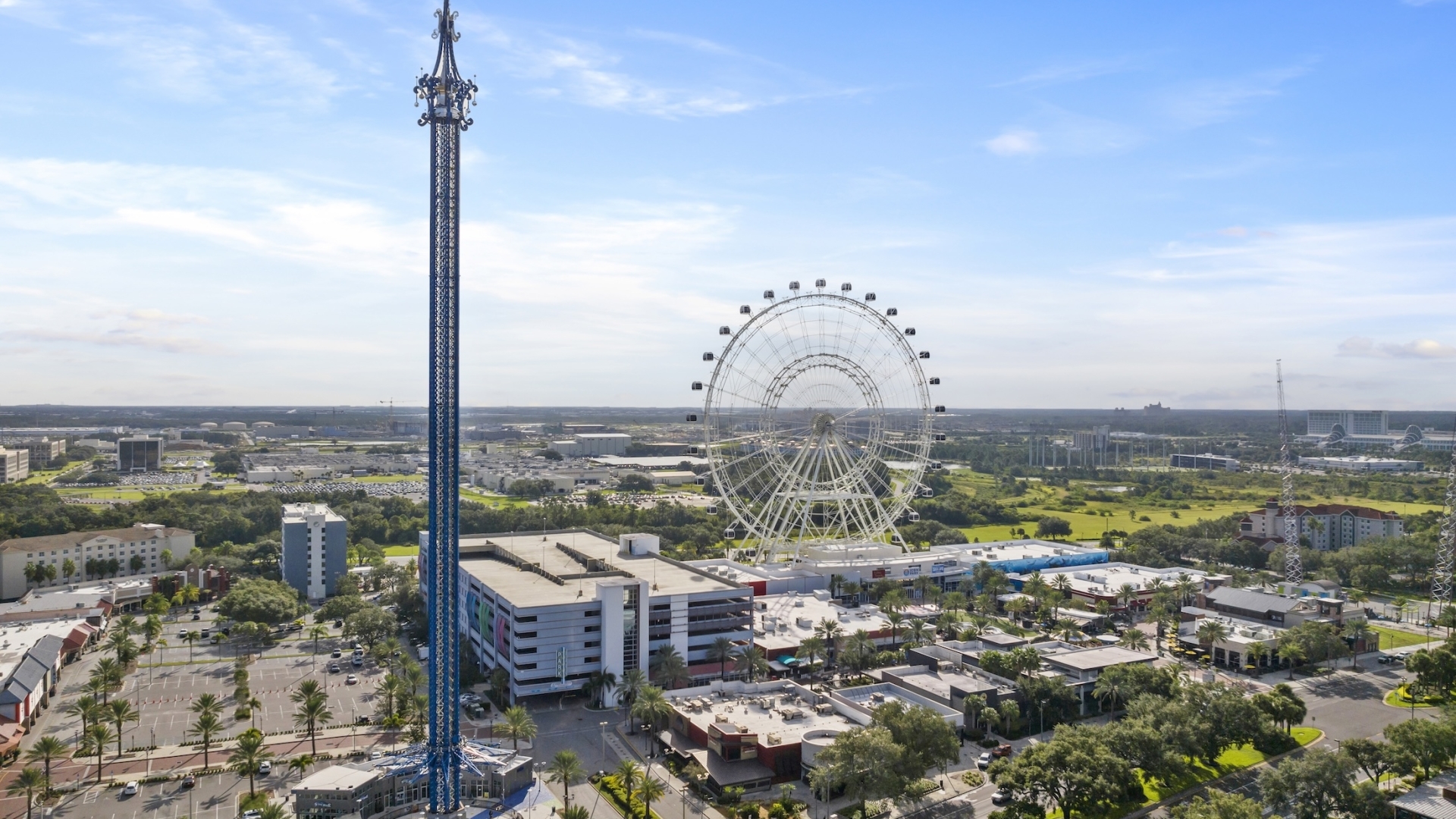 An aerial view of International Drive in Orlando, featuring the tall blue StarFlyer tower and the ICON Park observation wheel.