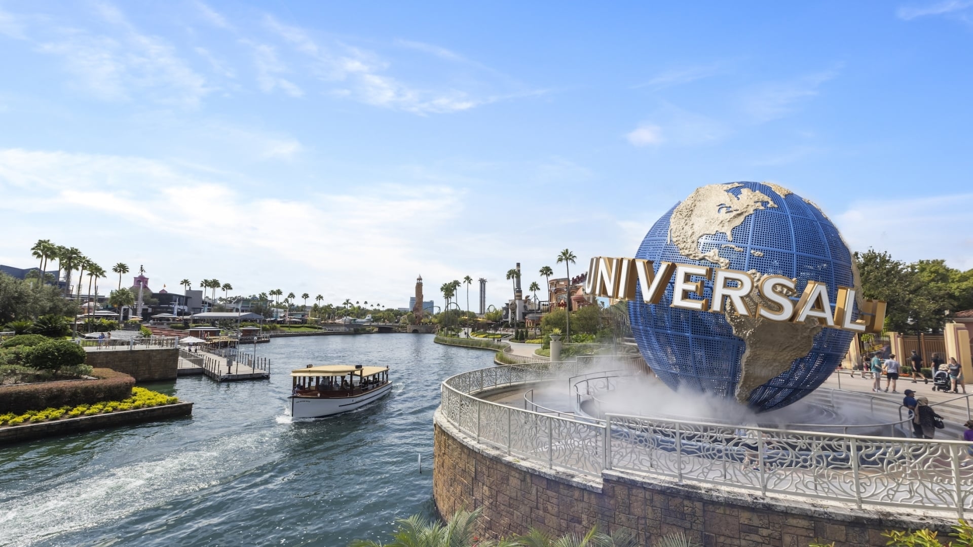 The iconic rotating Universal Studios globe in front of a waterway with a transport boat at Universal CityWalk Orlando.