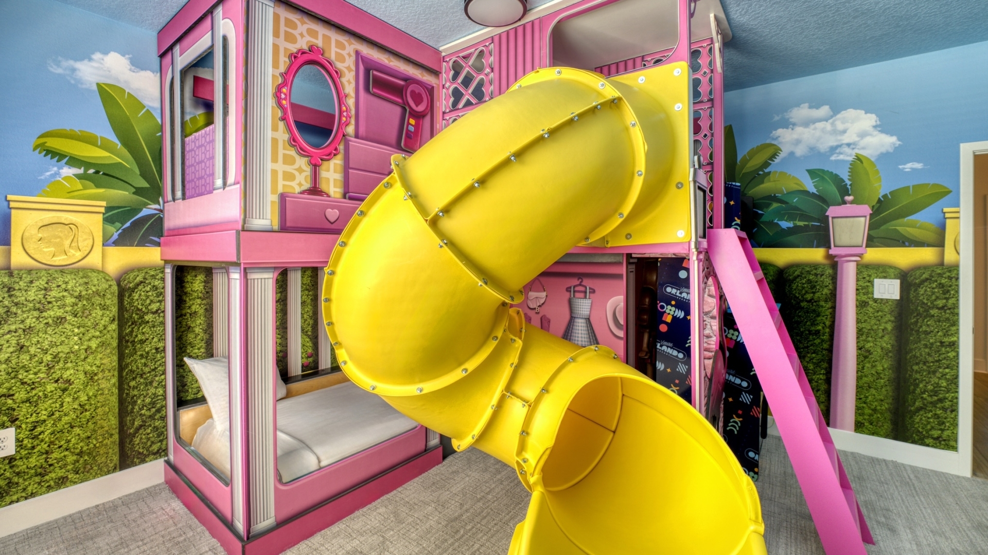 A vibrant pink, fashion-doll-themed children’s bedroom featuring custom bunk beds, a winding yellow tunnel slide, and tropical garden wall murals.