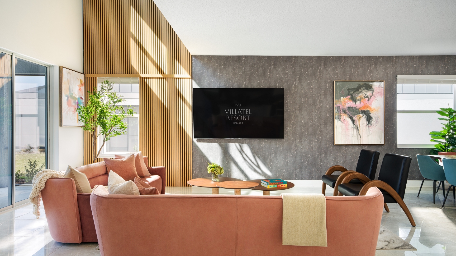 Modern open-concept living area with a curved rose-colored sofa, wall-mounted TV, and high-end finishes.